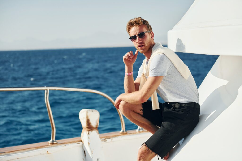 Posing for a camera. Young male tourist is on the yacht on the sea. Conception of vacation